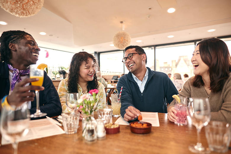 Visitors round a table in the Rooftop Restaurant enjoying a drink