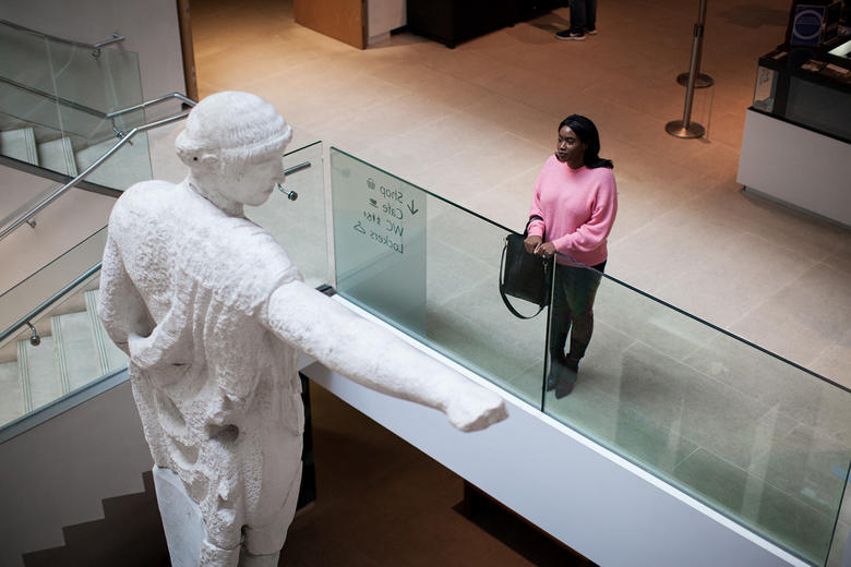 A woman stands on the first floor looking out over the museum atrium