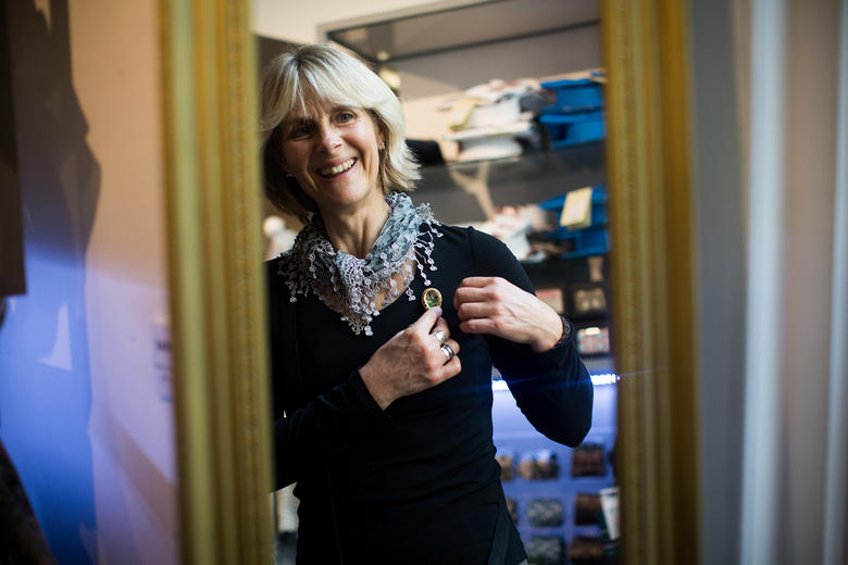 A woman looks in the mirror to try on a brooch in the Ashmolean Shop