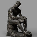Cast sculpture of a seated, nude man