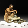 Painted clay model depicting a seated potter turning a pot on a wheel