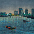 A view of a city by the water at night, with boats passing in the foreground