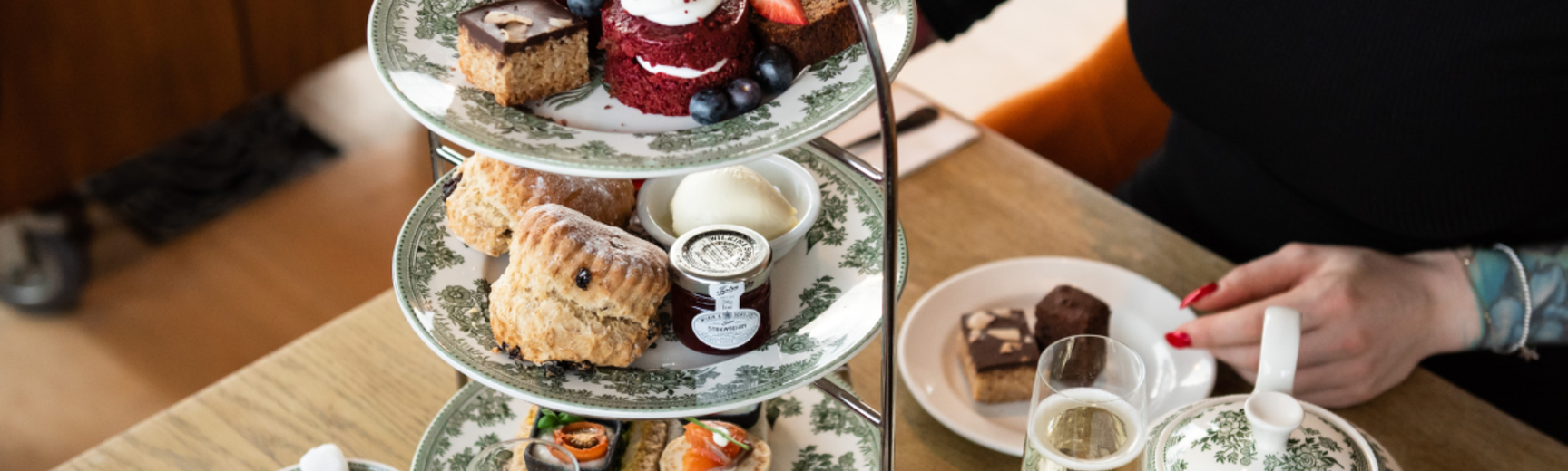 A table set for afternoon tea with sandwiches and cakes on decorated plates