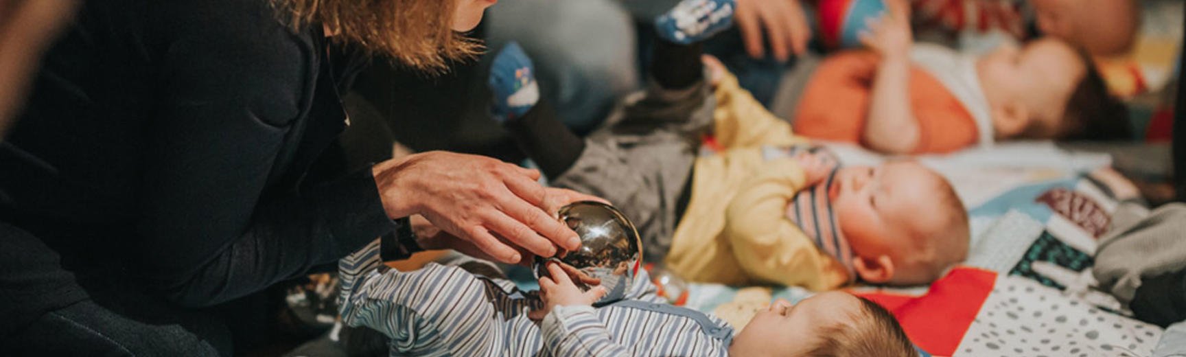 Image of new mums with their babies on blankets playing with silver ball toys