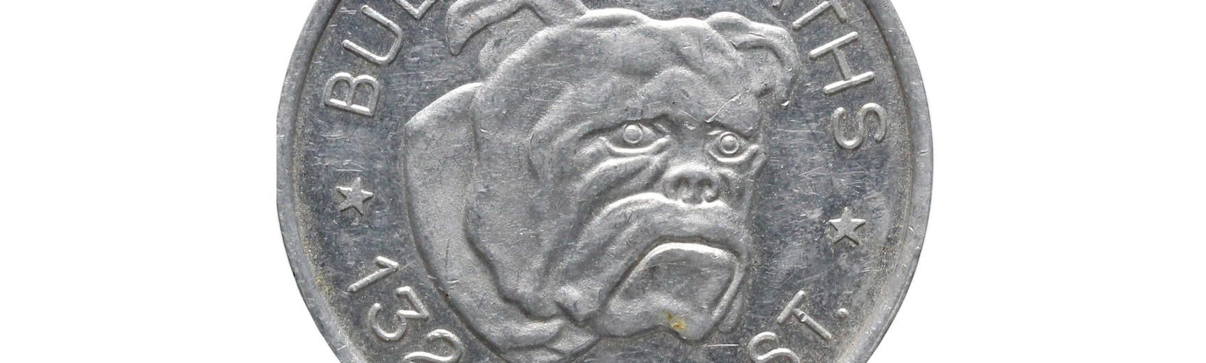 A silver token which shows the face of a bulldog. 'Bulldog Baths * 132 Turk St' is written around the image of the bulldog. 