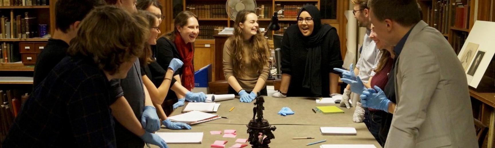 A group of students around a table of objects in a museum study room