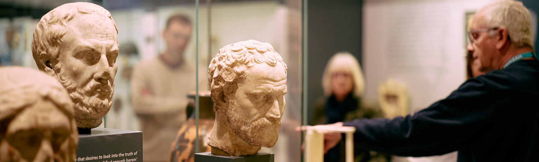 Gallery tour leader surrounded by heads and torsos 