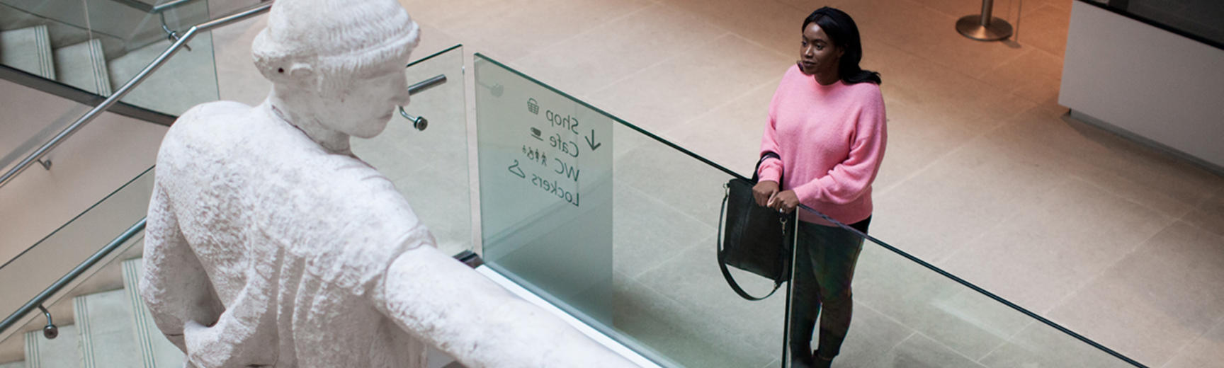 A woman stands on the first floor looking out over the museum atrium