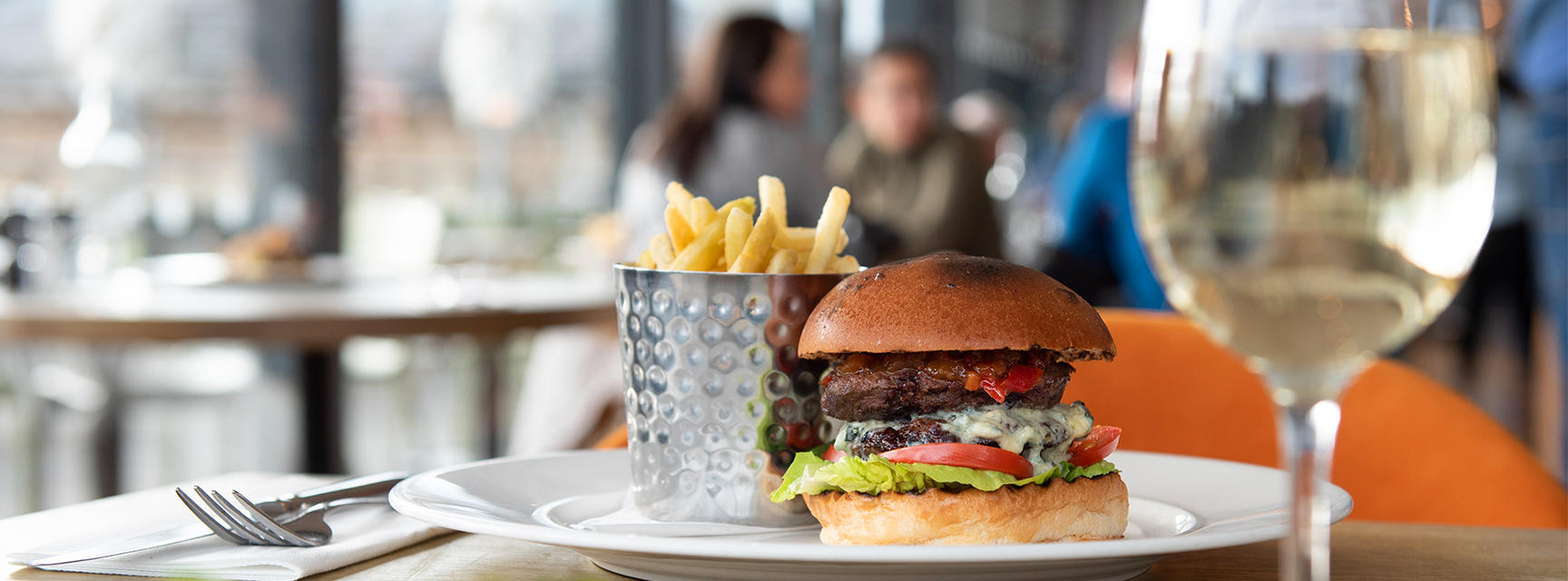 Burger and chips with wine and the Oxford skyline in the background- a dining scene in the Rooftop Restaurant