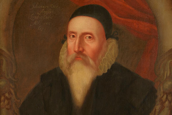 Painted portrait of John Dee who wears a black cap and a long white beard