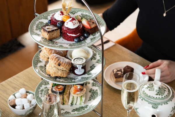 A table set for afternoon tea with sandwiches and cakes on decorated plates