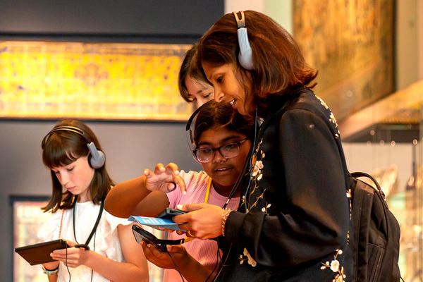 Family holding digital guides doing the Ashmolean Adventure in the textiles gallery 
