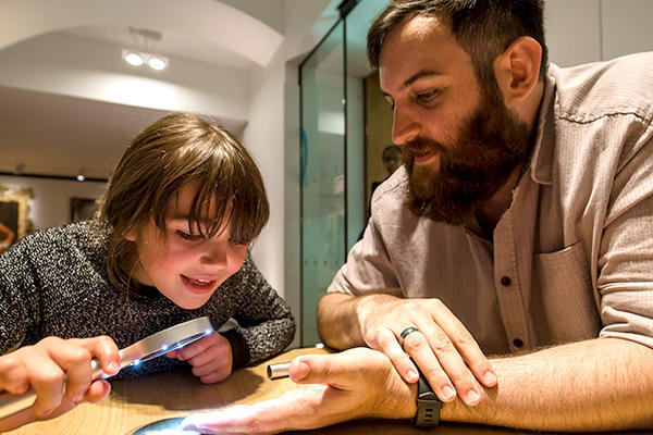Child uses a magnifying glass to look closer at coins in the museum