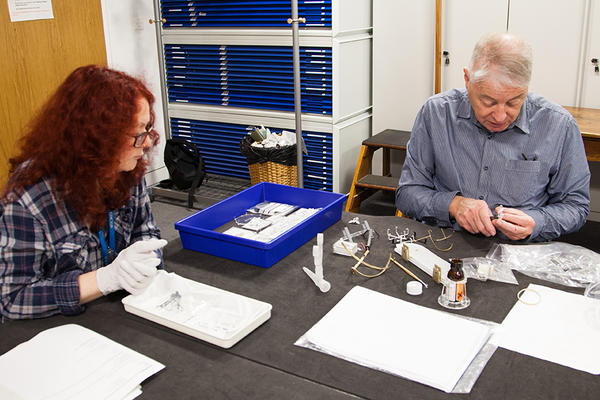 Seated researchers investigate objects at a table in a collections study room