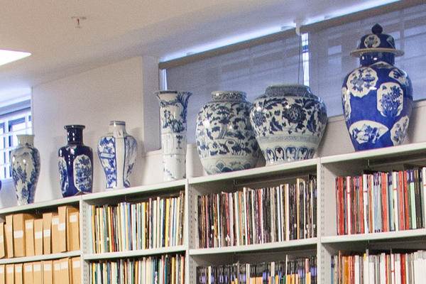 Tall Chinese vases sit atop a long bookcase