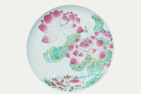 White ceramic plate decorated with pink flowers and fish in a pond