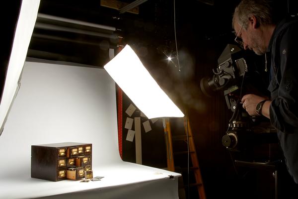 Staff member in the process of photographing an small antique drawers