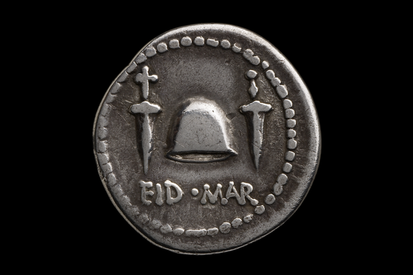 Silver coin with dotted edge detail, two daggers flanking a centrally position cap, and words EID MAR along bottom edge.