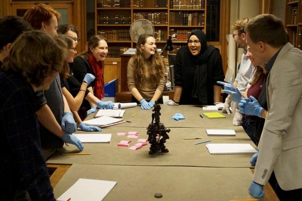 A group of students around a table of objects in a museum study room