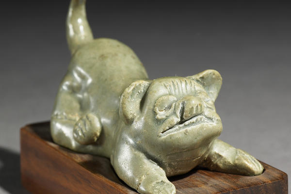 Greenware ceramic burial figure of a dog on a wooden block.