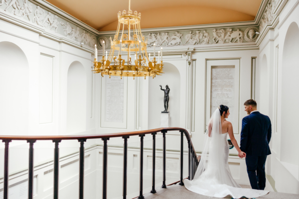 A married couple walk hand in hand down a staircase in the Ashmolean Museum