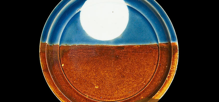 A round plate, the lower half orange, and the upper half blue with a large white circle in the centre