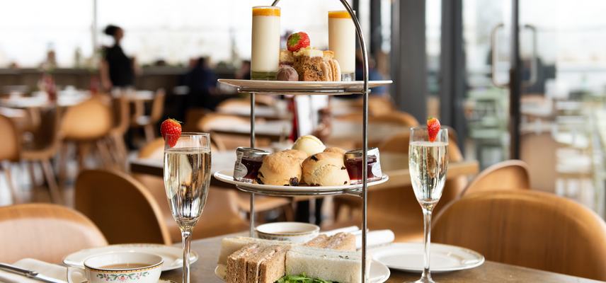 A tower of cakes and scones alongside teacups and glasses of prosecco