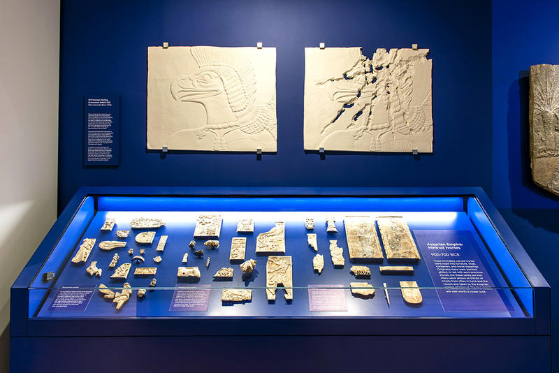 Ancient Middle East Gallery display showing reliefs on the wall and cabinet of many objects
