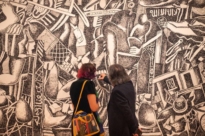 Black and white Panorama of Destruction tapestry in Dia al-Azzawi's exhibition, close up with visitors, of the 10-metre long artwork