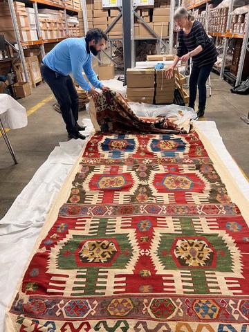 Dorothy Armstrong and a colleague examine an 18th century kilim from Ottoman Anatolia, from the Collection of Georgie Wolton, now in the Ashmolean