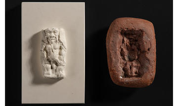 On the right, a red clay mould for making an amulet of Bes, the ancient Egyptian god who was part-lion and part-man with dwarfism. On the left is a white plaster recreation of the amulet.
