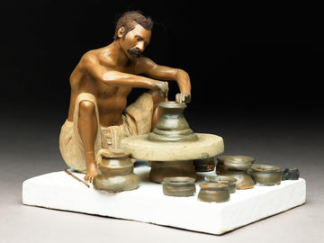 Model depicting a potter turning a pot on a wheel