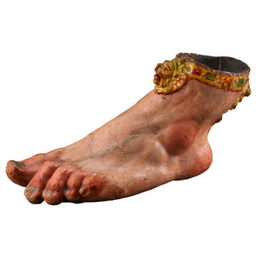 A realistic sculpture of a foot, with a decorative anklet