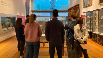 Krasis scholars discussing a Japanese lacquer cabinet in the West Meets East Gallery