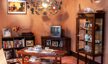 Shedding Light Caribbean living room display in the European Ceramics Gallery Shedding Light Caribbean living room display showing chandelier, photographs, tea set, china cabinet, tv, books and records